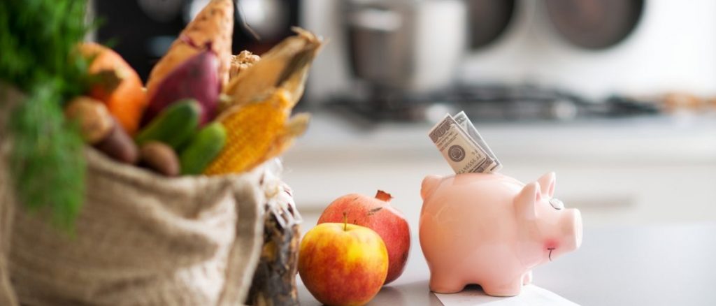 A piggy bank with a bag of vegetables and fruits.