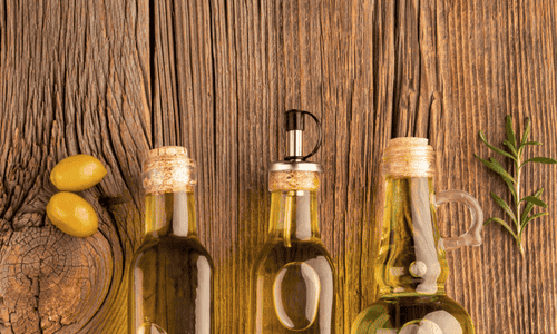 Yellow olives and oil bottles on wooden table top
